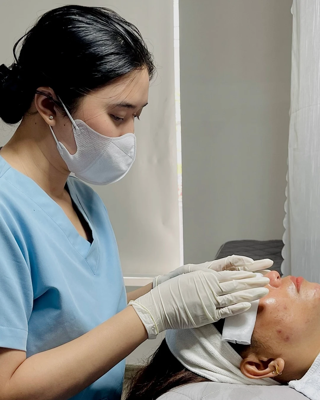 Kỹ thuật viên đeo găng đặt gạc làm dịu lên mặt khách sau thủ thuật tại Eternal Beauty Center — hướng dẫn chăm sóc được đưa theo đúng loại và thông số của buổi làm