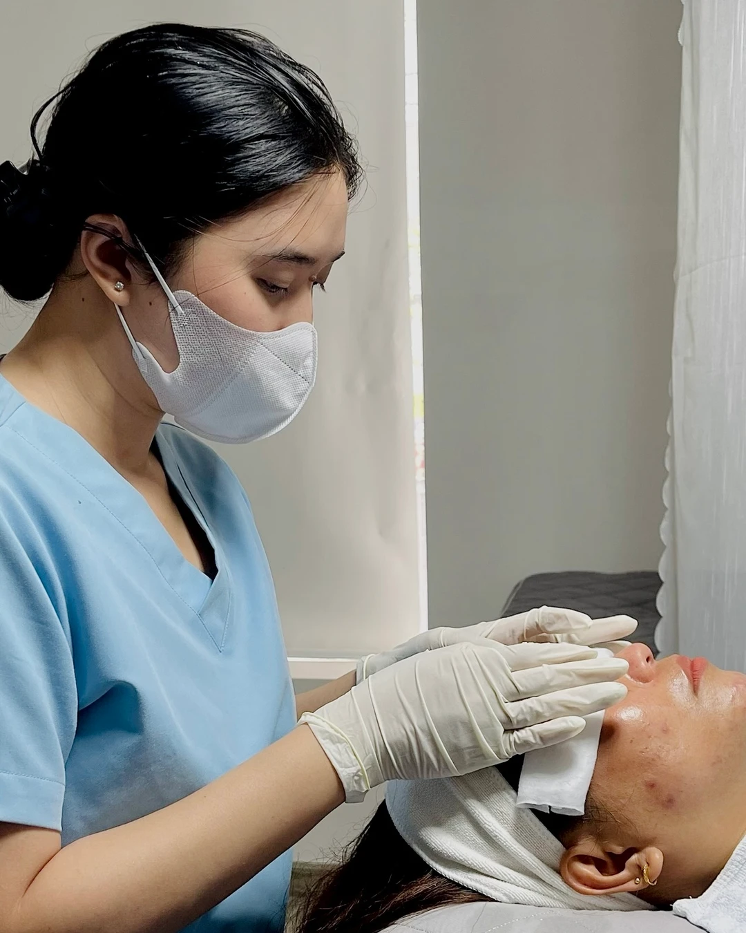 Gloved hands working with clean cotton pads on a client's cheek with inflamed spots at Eternal: a swollen, inflamed spot should not be squeezed, least of all right before a big day