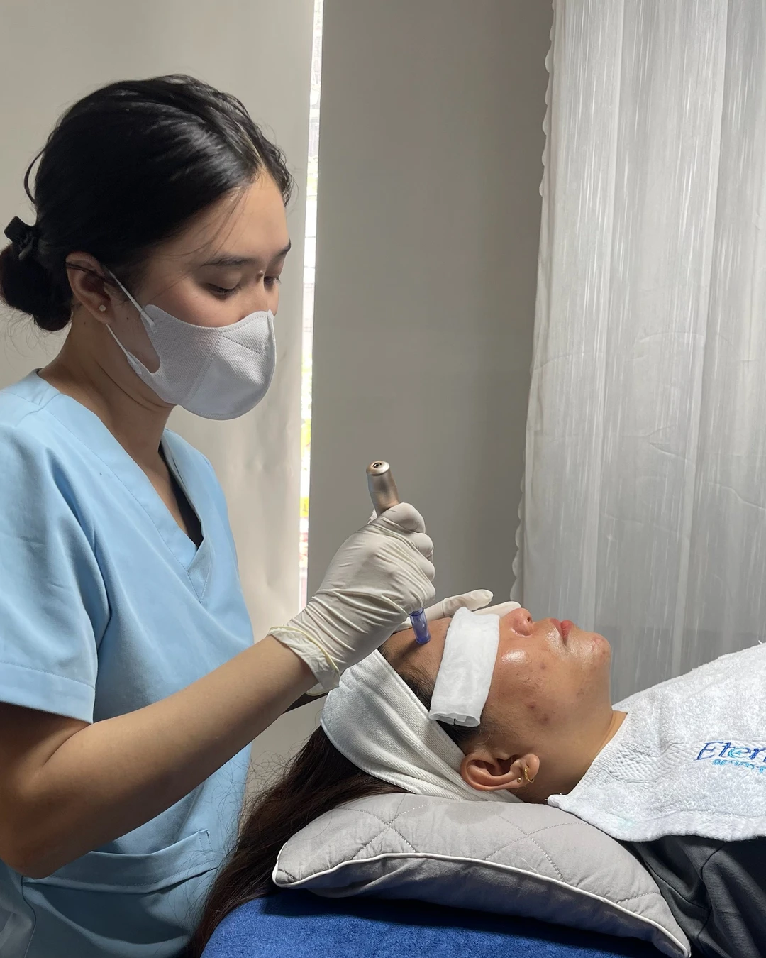Kỹ thuật viên Eternal thao tác bằng bút vi kim vô khuẩn trên vùng trán — khi vi kênh còn mở, chỉ sản phẩm vô khuẩn được chỉ định mới nên chạm vào da